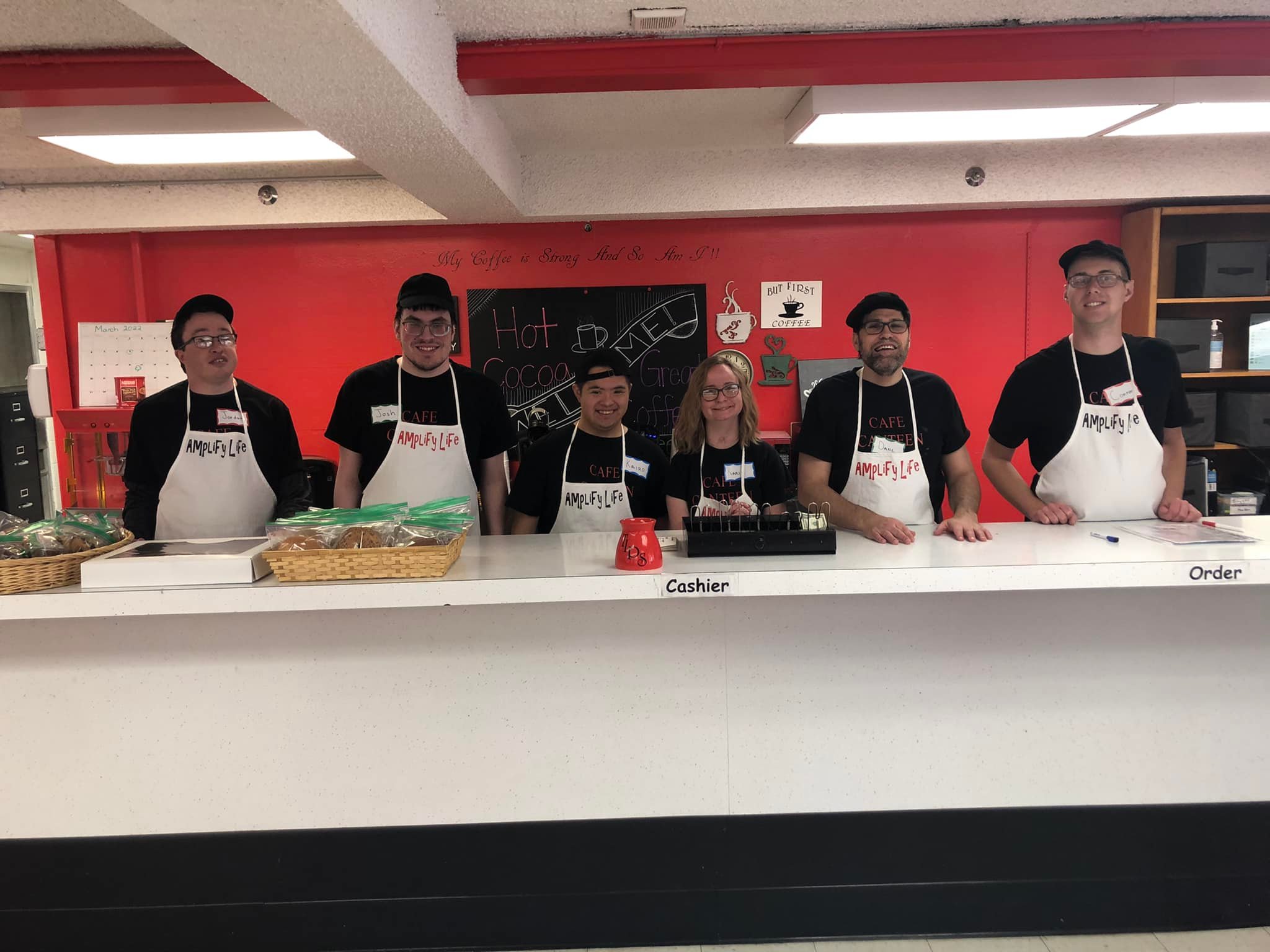 Café Canteen participants in aprons working behind the counter