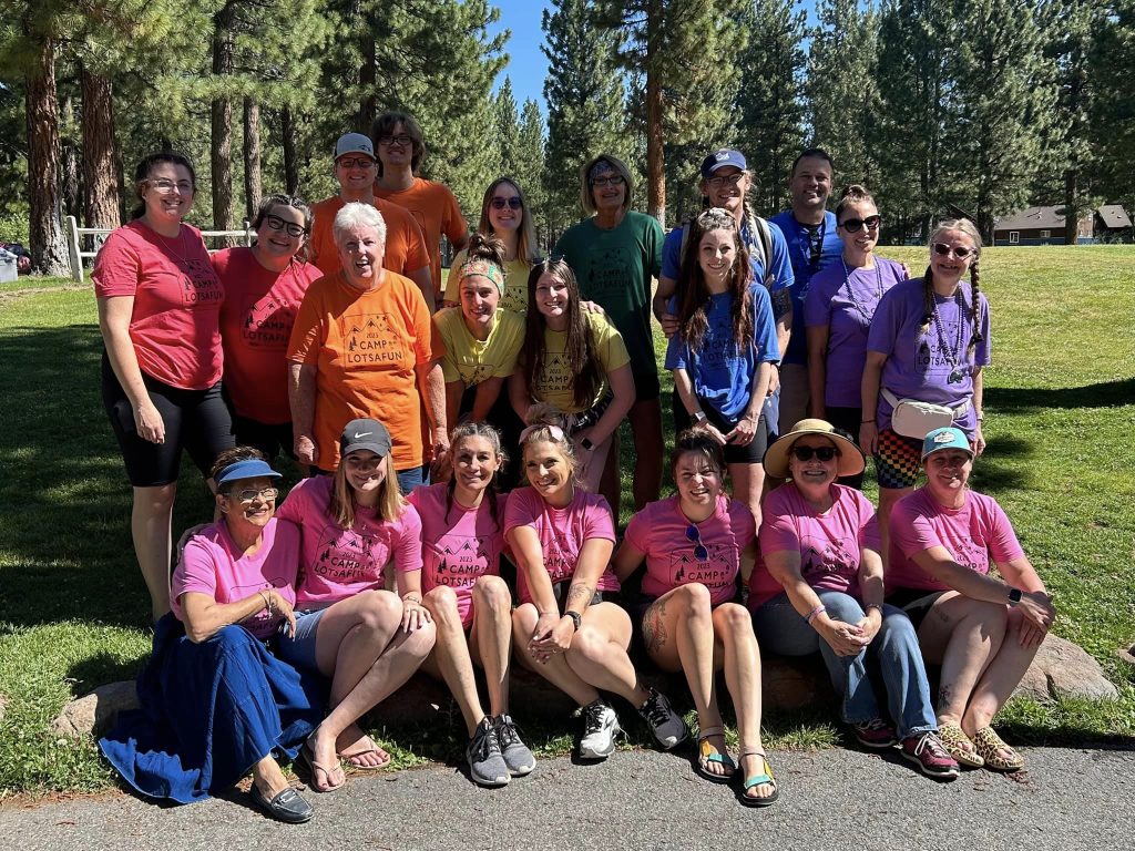 Amplify Life volunteers and participants in pink shirts gathered on the grass