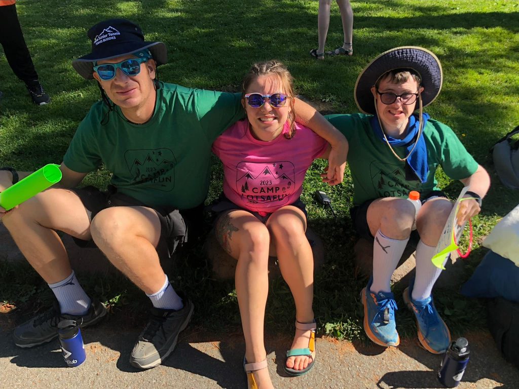 Volunteer sitting outdoors with two Amplify Life participants