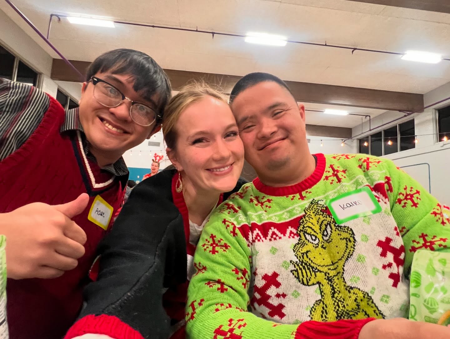 Staff member with two participants in holiday sweaters