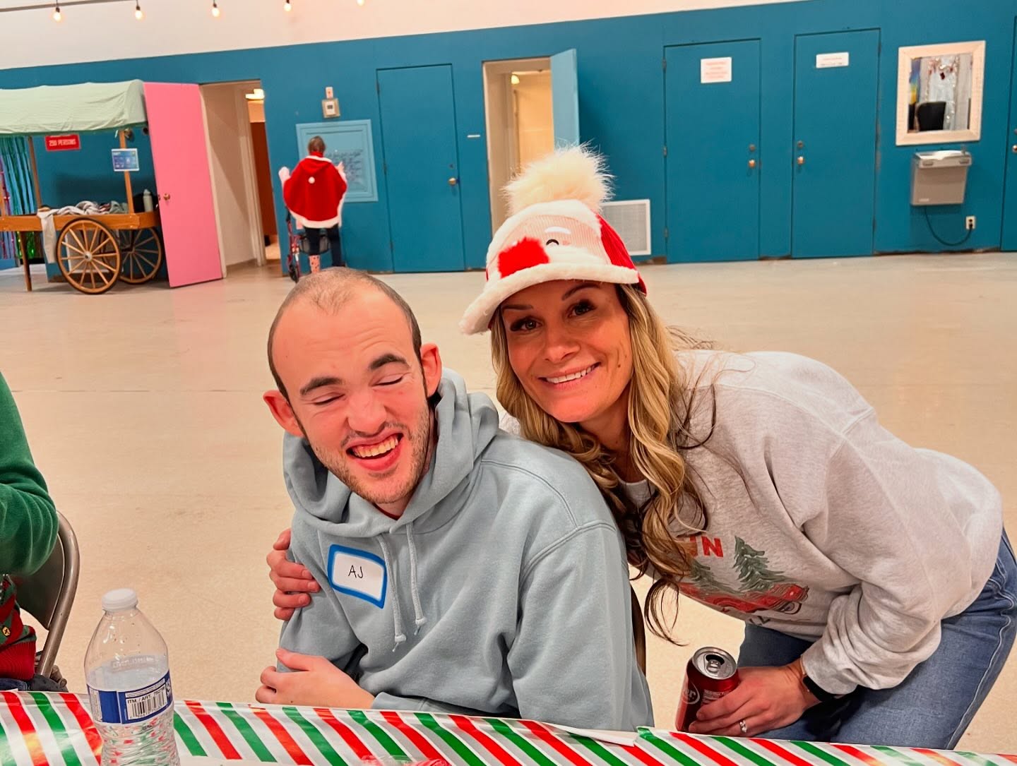 Staff member in a Santa hat hugging a participant at the holiday party