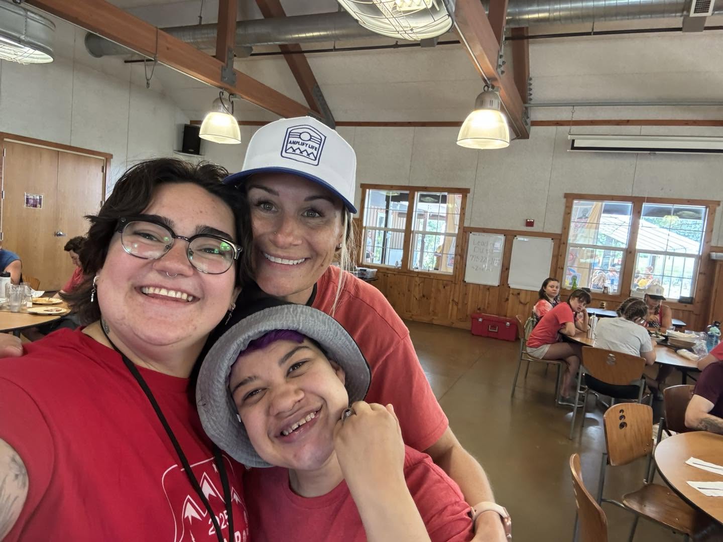 Staff members taking a selfie with a camper in the dining hall