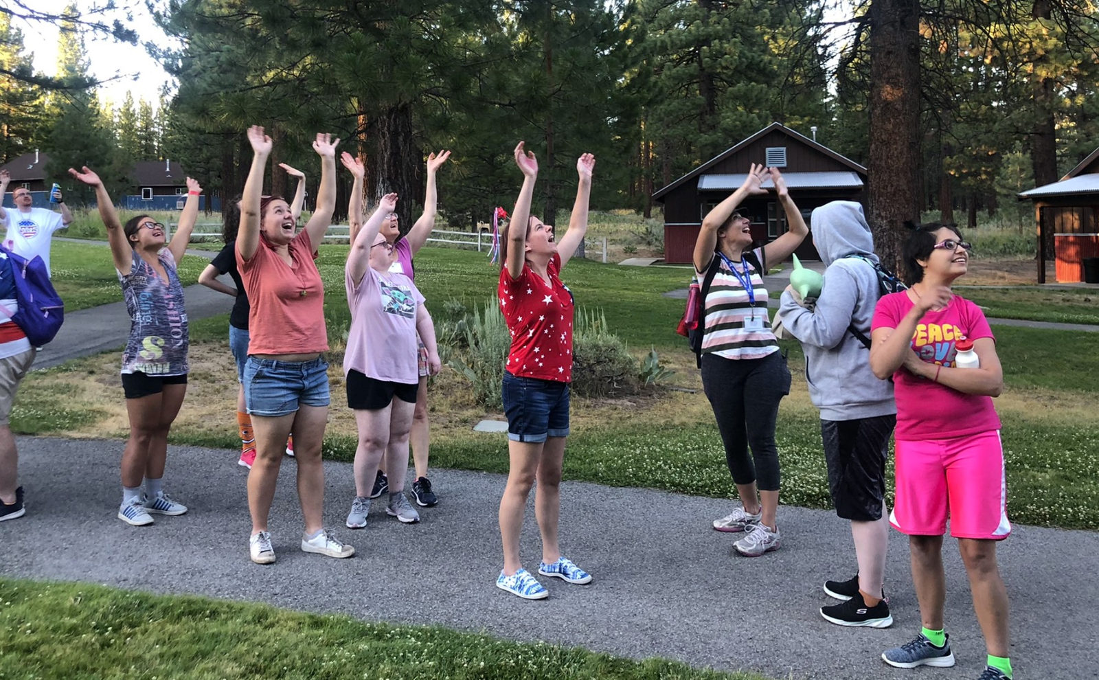 Campers raising their arms together outdoors at Camp Lotsafun